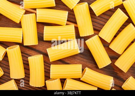 Pasta Rigatoni auf Holzhintergrund, Struktur des Draufsicht-Musters Stockfoto