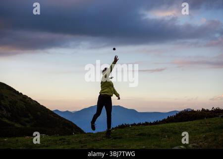Wanderer spielen während der goldenen Stunde Fang auf dem Bergrücken, mit mehrschichtigen Gipfeln und farbenfrohen Himmel, die perfekte Kulisse für Outdoor-Aktivitäten schaffen. Stockfoto