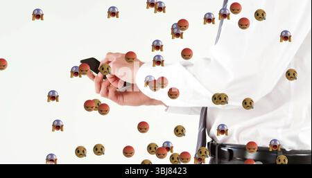 Stehender Mann im Anzug, der Smartphone im Studio hält, inmitten wütender schockierter besorgter Ikonen, Kopierraum Stockfoto