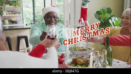 Wir feiern Seniorenfreunde in Weihnachtsmützen, die Weingläser am Esstisch zu Hause anschlagen, mit Huhn Stockfoto