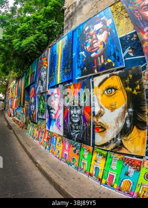 Eine lebendige Ausstellung von Street Art mit verschiedenen Porträts und farbenfrohen Türentwürfen entlang einer Wand in Cartagena, Kolumbien. Stockfoto
