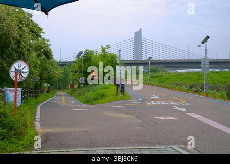 Incheon, Südkorea - 19. Mai 2025: Eine Serpentinenfahrt vom Ara Hangang Lock führt die Radfahrer in den Gangseo Hangang Park mit Jeonho Bridge Visi Stockfoto