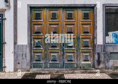 Verzierte Vintage Holztür Mit Abgenutzter Lackstruktur. Europäische Architektur, alter Eingang, verwittertes Holz, rustikale Fassade, historische städtische Details. Hoch Stockfoto