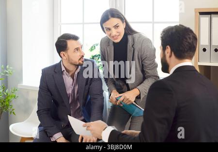 Drei junge Geschäftsleute im Büro sprechen und diskutieren. Stockfoto