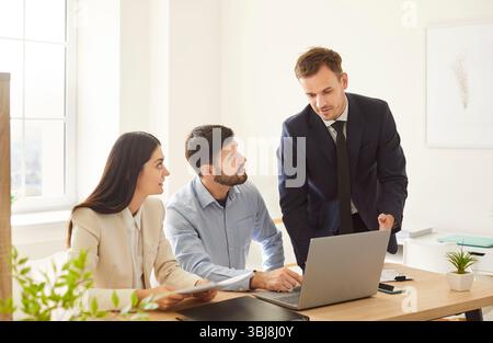 Drei Geschäftskollegen arbeiten in einem hellen Büro zusammen, führen Gespräche und arbeiten zusammen. Stockfoto
