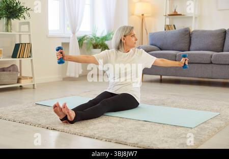 Seniorin, die mit Kurzhanteln trainiert, in Einer Heimtrainingsroutine Stockfoto