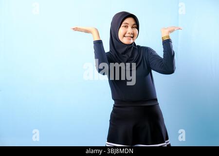 Eine Frau mit schwarzem Kleid und schwarzem Kopftuch. Sie hält ihre Hand in der Luft hoch Stockfoto