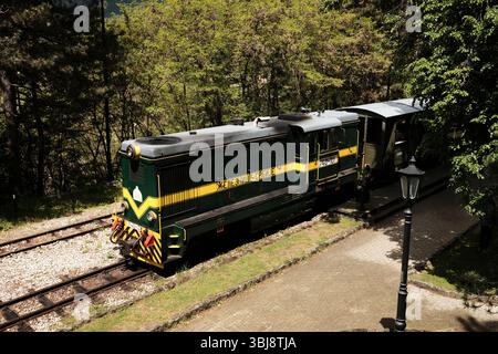 Blick von oben auf die berühmte grüne und gelbe Lokomotive Shargan Acht, die an einem sonnigen Frühlingstag am Bahnhof geparkt wurde. Sarganska Osmica - beliebter Tourist de Stockfoto
