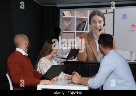 Gruppe von Personen, die an einer Geschäftskonferenz im Innenbereich teilnehmen. Lautsprecher auf Projektionsleinwand Stockfoto