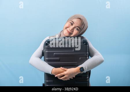Eine Frau hält einen schwarzen Koffer und lächelt. Konzept von Abenteuer und Spannung, während die Frau sich auf eine Reise vorbereitet. Stockfoto