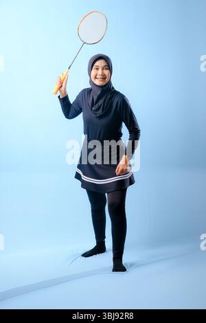 Eine Frau in einem schwarzen Rock und einer schwarzen Hose, die einen Badmintonschläger hält. Sie lächelt und ist glücklich Stockfoto