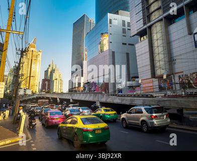 Bangkok, Thailand-07. April 2024-später Nachmittag, Sonnenlicht aus niedrigem Winkel reflektiert zufällig auf Hochhäuser und stark frequentierten Verkehr darunter während der Hauptverkehrszeit. Stockfoto