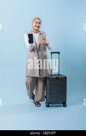 Eine Frau hält ein schwarzes Handy und zeigt darauf. Sie lächelt und ist glücklich Stockfoto