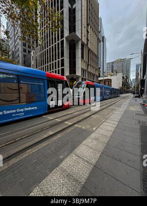 Moderne Straßenbahnen auf der George Street im zentralen Geschäftsviertel von Sudney an einem bewölkten Tag. Stockfoto