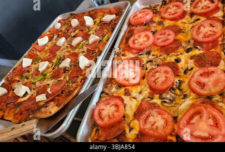 2 Pizzen, Pfefferwurst, Pilze und frische Tomatenscheiben sowie grüne Paprika und Wurst mit frischen Mozarella-Belägen. Stockfoto