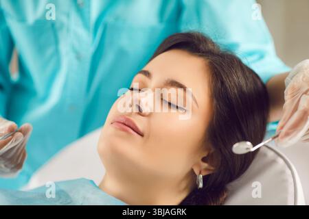 Eine junge Frau schloss ihre Augen im Zahnarztstuhl, Gesicht Nahaufnahme Stockfoto