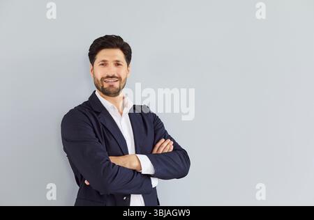 Porträt eines selbstbewussten bärtigen jungen Geschäftsmannes auf grauem Hintergrund. Stockfoto