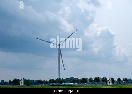 Blick auf eine ländliche Gegend mit einer Windturbine vor einem Himmel mit Sturmwolken Stockfoto