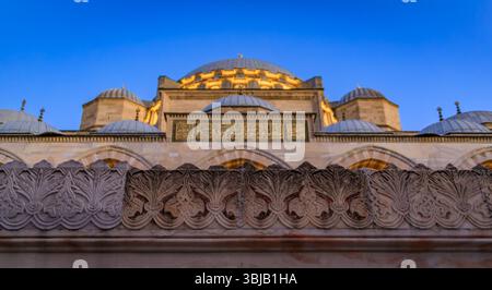 Eine detaillierte Nahaufnahme der Suleymaniye-Moschee mit kunstvollen Steinschnitzereien und den beleuchteten Kuppeln in der Abenddämmerung, der blauen Stunde bei Sonnenuntergang, in Istanbul, Türkei Stockfoto