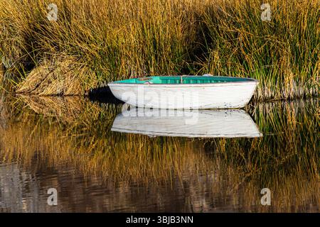 Kleines Boot, das neben dem Schilf der Totora am Titicacasee in Peru ankert, kann man die Reflexion im Wasser sehen Stockfoto