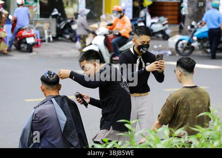 Ho Chi Minh, Vietnam - 9. Dezember 2022: Friseure schneiden die Haare von Kunden in einem Straßenfriseursalon in der Nähe des 23. September Parks. Stockfoto