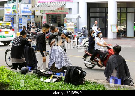 Ho Chi Minh, Vietnam - 9. Dezember 2022: Friseure schneiden die Haare von Kunden in einem Straßenfriseursalon in der Nähe des 23. September Parks. Stockfoto