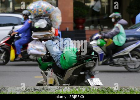 Ho Chi Minh, Vietnam - 9. Dezember 2022: Ein Mitarbeiter, der Lebensmittel in der Hand hat, legt sich in seinem Motorrad auf eine Bestellung in Saigon. Stockfoto