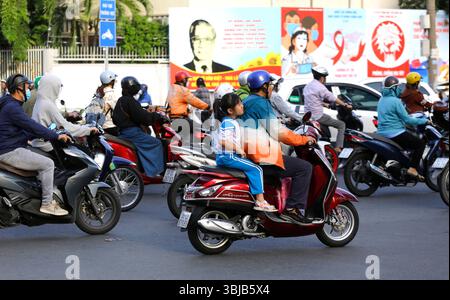 Ho Chi Minh, Vietnam - 8. Dezember 2022: Ein Mädchen fährt mit ihren Eltern auf einem Motorrad durch eine geschäftige Straße von Saigon. Stockfoto