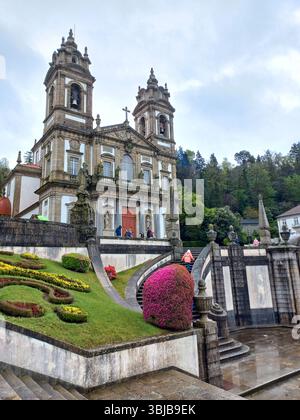 Braga Portugal 29. März 2024 Barockkirche von Bom Jesus do Monte mit Besuchern, die Treppen und Blumenbeete im Vordergrund klettern Stockfoto