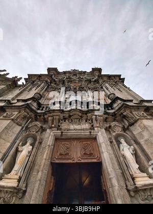 Porto, Portugal. März 30 2024 Detailansicht der reich verzierten Barockfassade von Igreja dos Clérigos mit verzierten Mauerwerken, Holztüren und Stockfoto