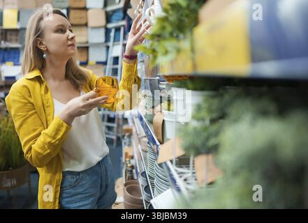Die Frau wählt Geschirr in einem Laden aus Stockfoto
