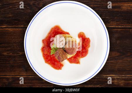 Fleischbällchen mit Tomatensauce und Kartoffelpüree auf Teller auf Holztisch, Blick von oben. Traditionelle mediterrane Küche Stockfoto