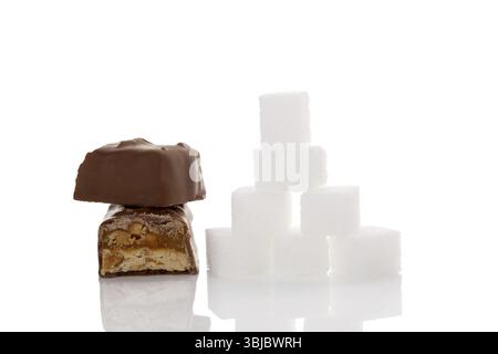 Schokoladenriegel und Zuckerwürfel isoliert auf weißem Hintergrund. Ungesunde Ernährung. Zucker und Kohlenhydrate Stockfoto