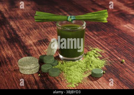 Grüne Superfood Chlorella, Weizengras, Gerstengras und Spirulina Pillen, Pulver und gemahlen auf hölzernem Hintergrund. Entgiftung Stockfoto