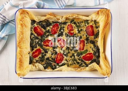 Vegetarischer Spinatkuchen oder Quiche mit Käse und Tomaten in einer Auflaufform von oben Stockfoto