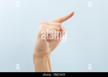 Amerikanische Gebärdensprache. Weibliche Hand mit dem Buchstaben Z isoliert auf blauem Hintergrund Stockfoto