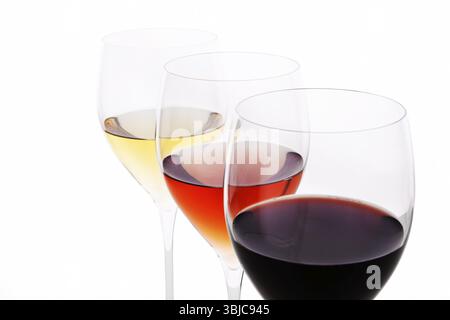 Drei elegante Kristallweingläser mit Rot-, Rosen- und Weißwein isoliert auf weißem Hintergrund Stockfoto