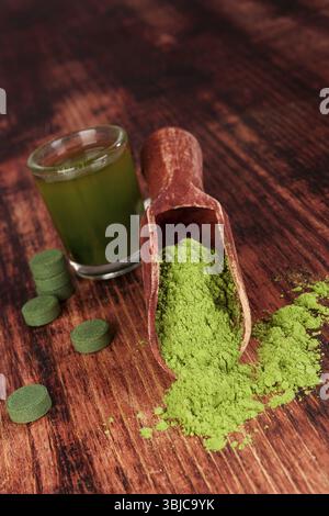 Nahrungsergänzungsmittel Chlorella, Spirulina und Weizengras auf hölzernem Hintergrund. Pillen, grünes Getränk und gemahlenes Pulver. Grüne Superfood. Alternative Stockfoto
