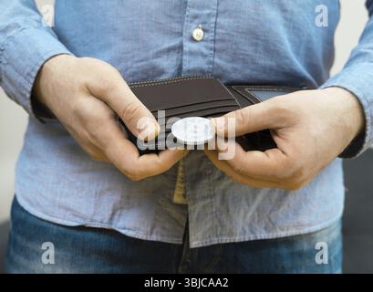 Mann mit einer physischen Version von silbernem Bitcoin Stockfoto