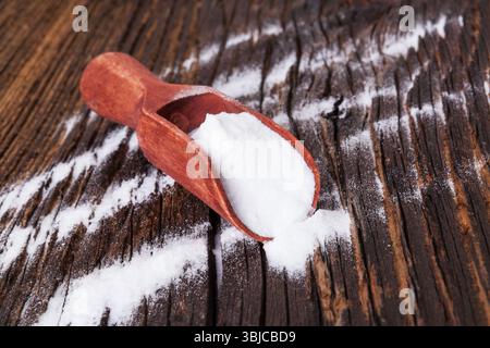 Backpulver auf Holzlöffel auf braunem, strukturiertem Hintergrund Stockfoto