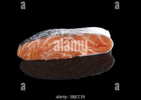 Roher frischer Lachsstück isoliert auf schwarzem Hintergrund. Fisch und Meeresfrüchte, minimalistischer Stil Stockfoto