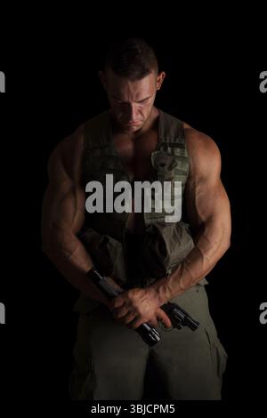 Soldat mit Pistole und Taschenlampe in grüner Uniform, stolz isoliert auf schwarzem Hintergrund. Armee, Sicherheit und Schutz Stockfoto