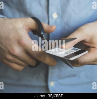 Mann schneidet Kreditkarte mit einer Schere Stockfoto