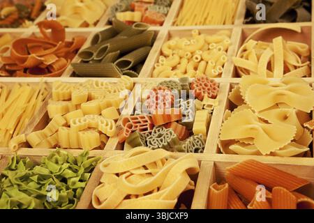 Verschiedene farbige Nudelsorten in Holzkiste Stockfoto