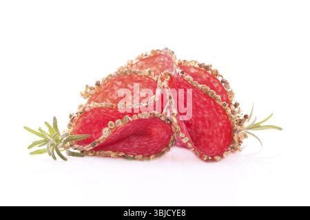 Luxuriöse Salamischeiben mit frischen Kräutern auf weißem Hintergrund. Kulinarisches Fleischesskonzept Stockfoto