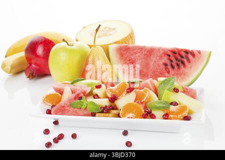 Farbenfroher Obstsalat und Obst auf weißem Teller isoliert. Frischer Sommer-Hintergrund. Wenn es darum geht, richtig zu essen und Sport zu treiben, gibt es keine, die ich anfangen werde Stockfoto