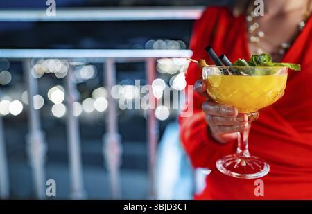 Frau in rotem Kleid trinkt Mango-Daiquiri-Cocktail Stockfoto