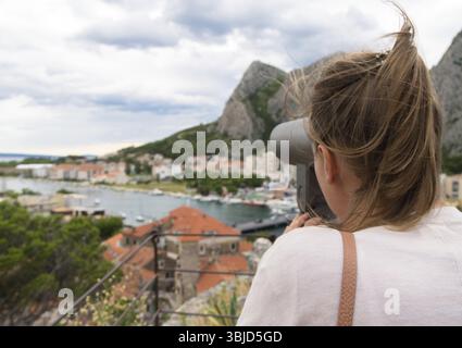 Frau, die ein Münzteleskop benutzt Stockfoto