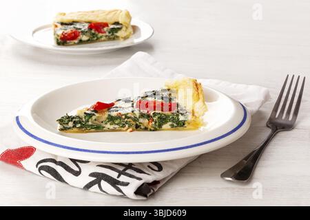 Vegetarische Quiche. Stück Kuchen mit Spinat und Tomaten. Kulinarisches Essen Stockfoto