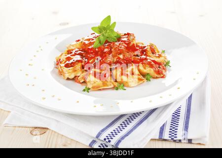 Tortellini mit Tomatensauce auf weißem Teller. Traditionelle italienische Pasta Stockfoto